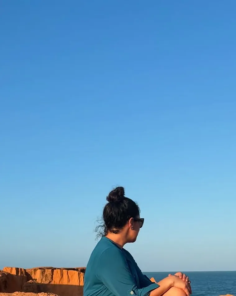 Sentada na falésia, olhando o mar